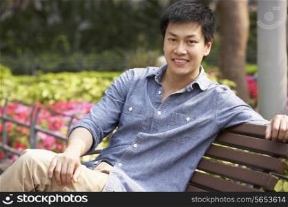 Young Chinese Man Relaxing On Park Bench