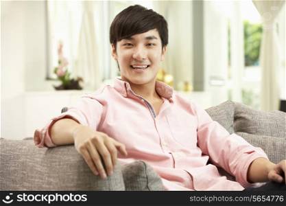 Young Chinese Man Relaxing On Sofa At Home