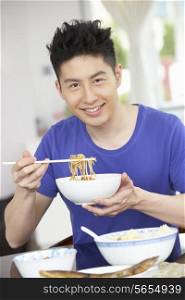 Young Chinese Man Sitting At Home Eating Meal
