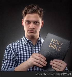 Young christian man showing showing with determination a Holy Bible (concept against temptation by God&rsquo;s Word)
