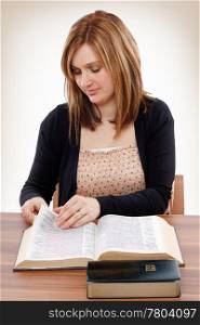 Young christian woman turning pages of the Bible searching for promises