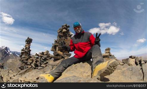 Young climber sitting on the top of a rocky mountain wearing red coat during a sunny day. Young climber sitting on the top of a rocky mountain during a sunny day