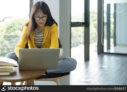 Young collage student using computer and mobile device studying online. Education and online learning.