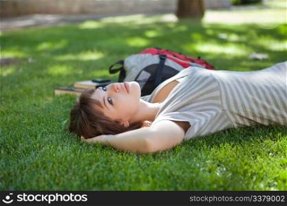 Young college student lying on grass at campus lawn