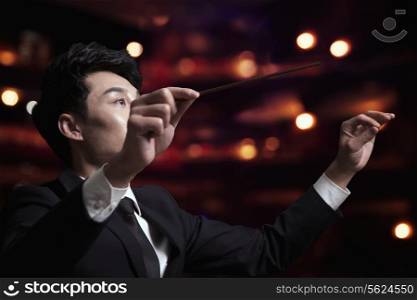 Young conductor with baton raised at a performance