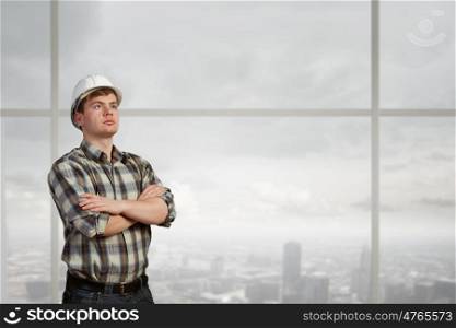 Young confident builder man with arms crossed on chest