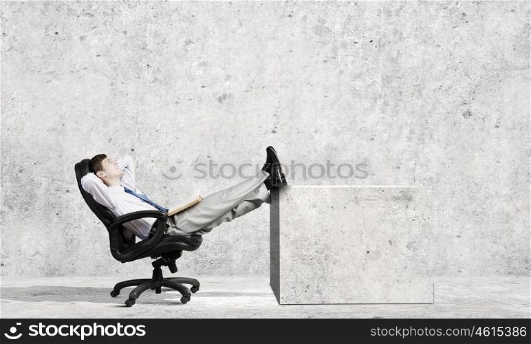 Young confident businessman sitting in chair with legs up. Successful businessman