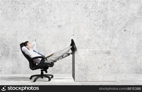 Young confident businessman sitting in chair with legs up. Successful businessman