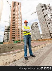 Young construction engineer standing in front of buildings under construction