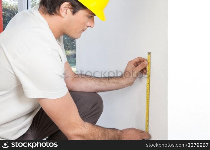 Young contractor measuring the wall for repairing