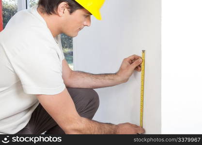 Young contractor measuring the wall for repairing