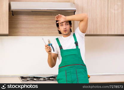 Young contractor repairing oven in kitchen 