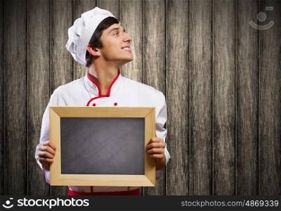 Young cook. Handsome cook holding blank chalk board. Place for text