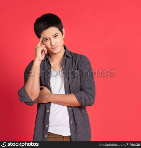 Young cool handsome asian man looking sideways with doubtful and skeptical expression isolated on rad background in studio.