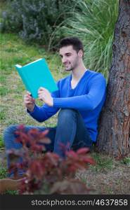 Young cool man reading a book next a tree