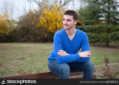 Young cool man sitting on a bank in the park