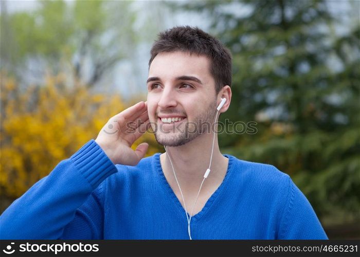 Young cool men dressed in blue in the park listening music with earphones