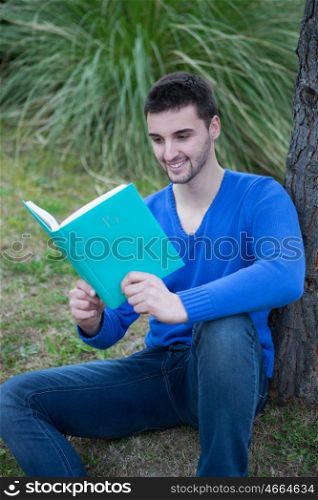 Young cool men dressed in blue in the park reading a book