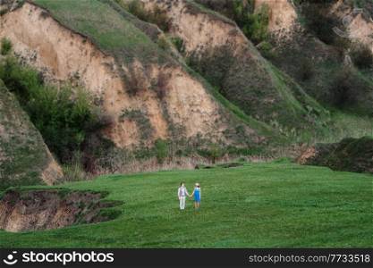 young couple a guy and a girl are walking in the green mountain hills
