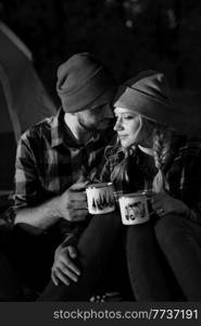 Young couple a guy and a girl in bright knitted hats stopped at a c&ing near the fire