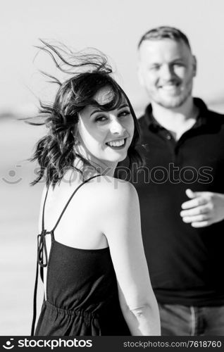 young couple a guy and a girl with joyful emotions in black clothes walk through the snow white desert