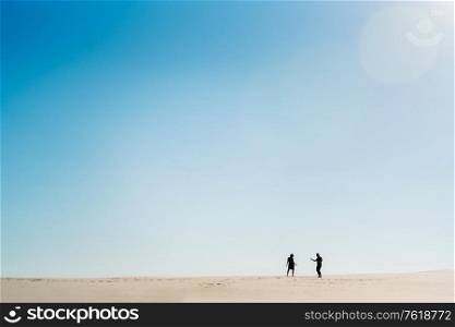 young couple a guy and a girl with joyful emotions in black clothes walk through the snow white desert