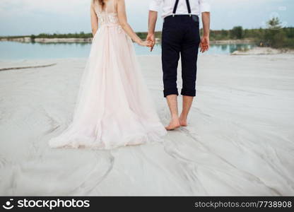 young couple a guy in black breeches and a girl in a pink dress are walking along the white sand of the desert