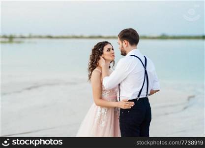 young couple a guy in black breeches and a girl in a pink dress are walking along the white sand of the desert