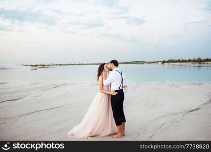 young couple a guy in black breeches and a girl in a pink dress are walking along the white sand of the desert