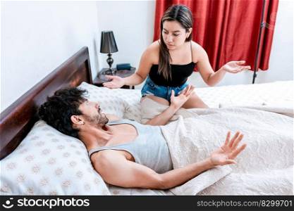 Young couple arguing in bed room. Husband fighting with his wife in bed. Concept of couple problems in bed. Upset woman with husband in bedroom bed