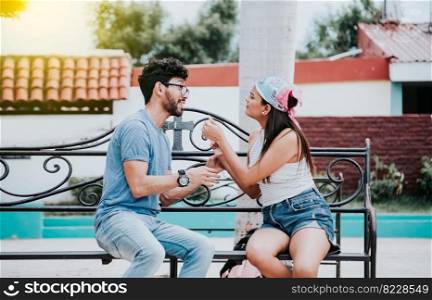 Young couple arguing sitting on a park bench, Concept of aggressive couples in the park. Upset couple arguing on a park bench. Man arguing with his girlfriend sitting in a park