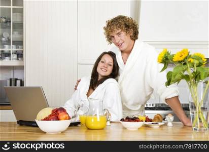 Young couple at breakfast, wearing bathrobes in a kitchen and looking at the camera