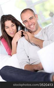 Young couple at home listening to music on internet