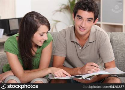 young couple at home skimming through catalogue