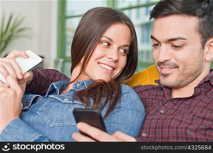 Young couple at home using mobile phones