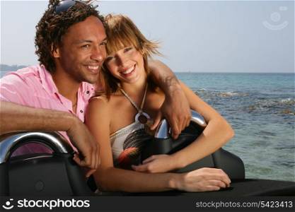 Young couple at the beach stood by convertible car