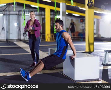 young couple athletes working out their arms using boxes at crossfitness gym. athletes working out their arms