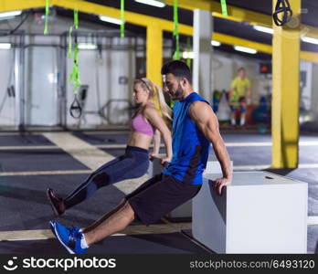 young couple athletes working out their arms using boxes at crossfitness gym. athletes working out their arms