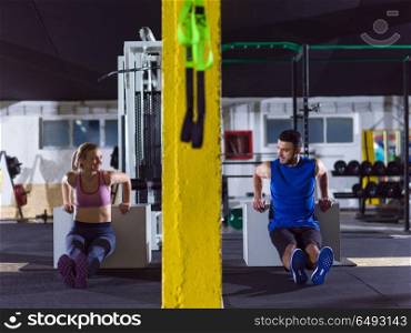 young couple athletes working out their arms using boxes at crossfitness gym. athletes working out their arms