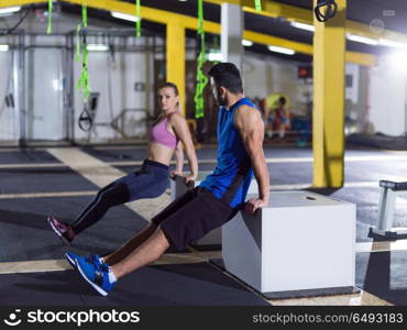 young couple athletes working out their arms using boxes at crossfitness gym. athletes working out their arms