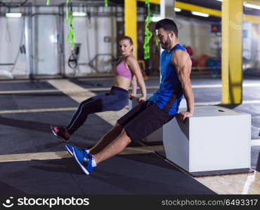 young couple athletes working out their arms using boxes at crossfitness gym. athletes working out their arms