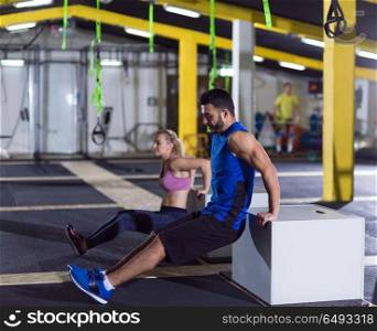 young couple athletes working out their arms using boxes at crossfitness gym. athletes working out their arms