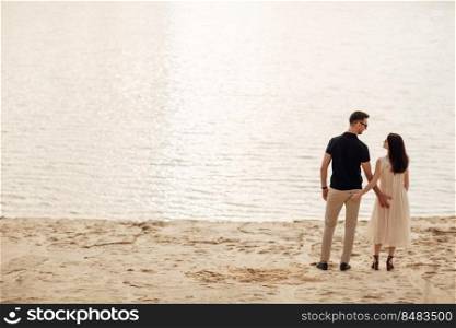 Young couple back standing near to the lake on nature. Romantic man and woman are hugging outdoors. Happy moments together. love story.. Young couple back standing near to the lake on nature. Romantic man and woman are hugging outdoors. Happy moments together. love story