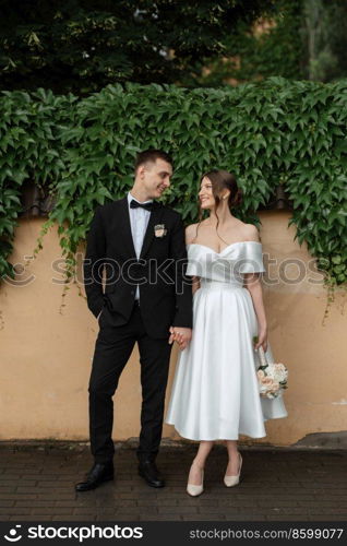 young couple bride and groom in a white short dress walking in the rain