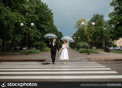 young couple bride and groom in a white short dress walking in the rain