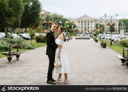 young couple bride and groom in a white short dress walking in the rain