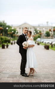 young couple bride and groom in a white short dress walking in the rain