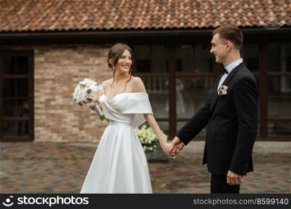young couple bride and groom in a white short dress walking in the rain