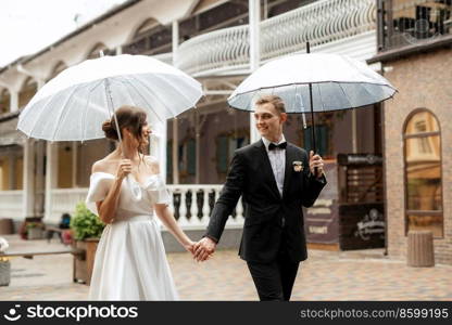 young couple bride and groom in a white short dress walking in the rain