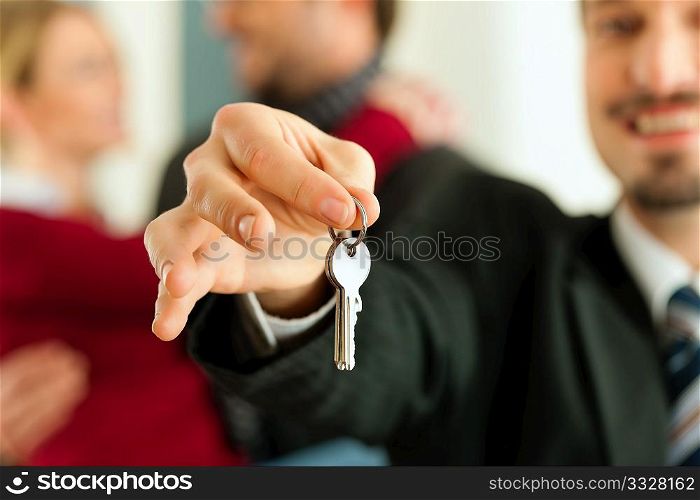Young couple buying or renting a home or apartment, they are meeting the owner or real estate broker who has the keys; FOCUS on keys